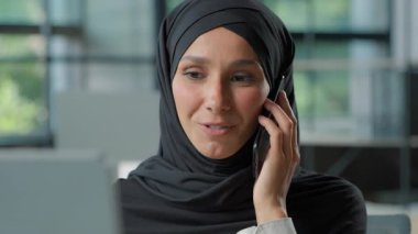 Arap tesettürlü, tesettürlü, cep telefonlu, mutlu Müslüman iş kadını, kadın, iş kadını, akıllı telefon konuşmaları bilgisayar satış temsilcisine danışmak, müşteriye danışmak.