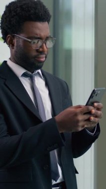 Akıllı telefonlara ciddi bakan Afro-Amerikalı işadamı cep telefonu iş adamı üzgün ofis çalışanı dijital iletişim stresinden endişeleniyor.