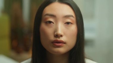 Portre tatmin olmuş Asyalı kadın kameraya bakıp gülümsüyor. Stüdyoda gülümsüyor. Çinli kız, Koreli, gülümsüyor. Dişli, dişlek dişli, doğal cilt estetiği olan kadın.