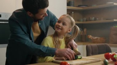 Gülümseyen aile yemekleri neşe dolu sebze salatası evde sağlıklı sebze salatası, evlat edinilmiş kız çocuk baba ile birlikte salatalıkları dilimlemeyi öğreniyor ve sevimli kızına yardım ediyor.