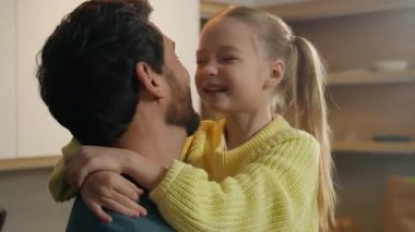 Evlat edinilmiş küçük kız çocuk çocuk ve baba burunları birbirine değdiriyor. Mutfaktaki mutlu beyaz aileyi eğlendiriyor. Babalar günü birlikte evde sevgi dolu bir babaya sarılıyorlar.