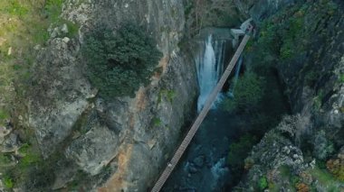 Sierra Nevada 'da şelalesi olan derin kanyondaki tahta köprü. Etrafı kayalık uçurumlarla çevrili. Macera dolu orman.
