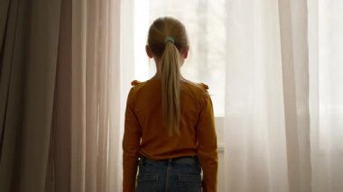 Kafkasyalı küçük kız çocuğu kız çocuğu. Pencereden sokağa bakıyor. Ailesinin odadan çıkmasını bekliyor.