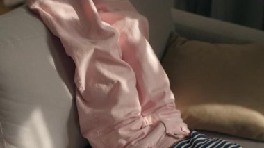 Kafkasyalı çocuk cep telefonuyla kanepeye uzanmış, gülüyor, gülüyor, komik videolar seyrediyor, akıllı telefon bağımlısı, reşit olmayan kızı internete yüklüyor.