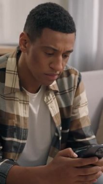 Üzgün, üzgün, afro-amerikan erkek. Evde cep telefonuyla ilgili negatif ruh hali. Erkek hayal kırıklığı yaşıyor.