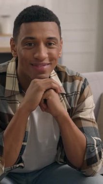 Mutlu, mutlu, gülümseyen, Afro-Amerikalı, etnik erkek, kameraya bakıyor. Kaygısız bir şekilde kanepeye uzanıyor. Oturma odasındaki kanepede dinleniyor.