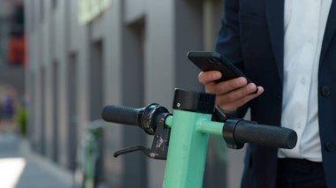 Tanımlanamayan bir iş adamı, şehrin bilinmeyen işadamlarından elektrikli scooter kiralamak için cep telefonu uygulaması kullanıyor. Akıllı telefonla ödeme yapıyor.