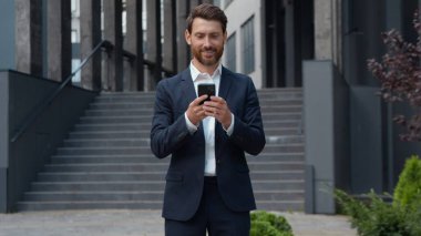 Şehirdeki başarılı iş adamlarından biri cep telefonuyla cep telefonu kullanıyor e-posta kontrolü yapıyor yetişkin erkek yöneticiler sosyal medyada sohbet ediyor. Yüksek