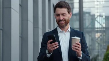 Gülümseyen Kafkasyalı bir iş adamı elinde telefonla şehirde yürüyor. Orta yaşlı bir iş adamı. Elinde cep telefonu ve kağıt bardakla şehir merkezine gidiyor.