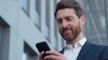 Yakın plan, Kafkasyalı bir iş adamı elinde cep telefonu ile şehir iş adamına bakıp gülümsüyor cep telefonu uygulaması ile internet sohbeti yapan akıllı telefon uzmanını kullanarak e-posta gönderiyor.