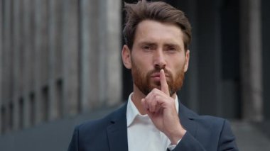 Kafkasyalı iş adamı sessiz hareketler gösteriyor. Sessiz ol. Şehirli işadamı, işçi, girişimci, parmak ucunda gizli bilgi sembolü hakkında konuşmayı yasaklıyor.