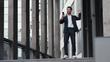 Başarılı, mutlu, Kafkasyalı iş adamı telefon bahsi kazanarak internet üzerinden kutlama yaparak şehir merkezindeki ofis binası yakınlarındaki erkek girişimciye teklif sunuluyor.