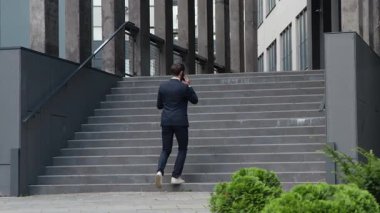 Kafkasyalı iş adamı merdivenlerde yürüyor telefon görüşmeleri yapıyor meçhul erkek girişimci yönetici merdivenlerden çıkıyor şirket binası merdivenlerinden yukarı çıkıyor akıllı telefonlardan bahsediyor