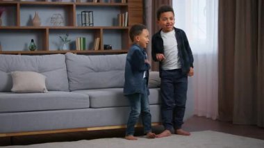 İki Afrikalı Amerikalı çocuk evde dans ediyor neşeli komik bir şekilde müzik yapıyor mutlu aile çocuklarına taşınıyor kardeşler şarkı söyleyerek dans ediyor etrafta gülüp eğleniyorlar. Yüksek