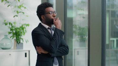 Yaratıcı, düşünceli, Afrikalı, Amerikalı, erkek, girişimci, iş adamı, fikir üreten, kurumsal bir çözüm üreten ofis müdürlüğü işinde kameraya ciddi bir şekilde bak.