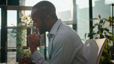 Mutlu Afrikalı Amerikalı iş adamı, güneşli ofiste bilgisayar kazanıyor. Erkek işadamı, iyi haberler okuyor. Kumarhane bahsini kazanan girişimci proje anlaşmasını heyecanla bekliyor.