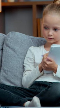 Kafkasyalı küçük tatlı liseli kız çocuk e-posta ile el kaldırmayı öğreniyor. İnternette özel ders vermeye hazır. Kanepe karantina karantinası üzerine bilgisayar ve defter ile ders dinliyor.