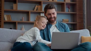 Evde mutlu bir beyaz aile babası ve küçük çocuk dizüstü bilgisayar kullanıyor. İnternetten komik videolar izliyorlar. İnternetten alışveriş yapıyorlar.