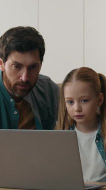 Kafkas ailesi ev mutfağında bilgisayar teknolojisiyle çevrimiçi Kafkas babası kız öğrenci kızına internet tarayıcıda yardım ediyor.