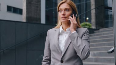 Ciddi bir şekilde kendinden emin, orta yaşlı beyaz iş kadını şirket binası yakınlarındaki iş kadını kadın girişimci iş kadını ile telefonda görüşüyor.