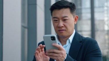 Asyalı mutlu iş adamı telefon kazanmasıyla şaşırdı Koreli iş adamının sevinç cep telefonu başarısı Japon yöneticinin şehirde cep telefonuyla iyi haberler okuması Çinli erkek kumarhane parası kazandı.