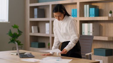 Odaklanmış Asyalı Çinli iş kadını neşeli kadın CEO 'su Koreli Japon iş kadını analiz eden belgeler rapor eden kağıt arama laptoplu bilgisayar yazılımları ofisin içinde