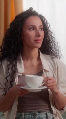 İspanyol kadın elinde fincanla kameraya bakıyor gülümsüyor Latin kadın mutlu ev hanımı kahveli çay içiyor göz açıp kapayıncaya kadar ev sahibinin hayalini kuruyor.