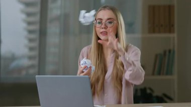 Öfkeli Kafkasyalı iş kadını konuşuyor. Video konuşuyor. Ofise gazete topları atıyor. İş kadını, iş kadını, iş kadını, konuşma, dizüstü bilgisayar konferansı, deli gibi bağırıyor.