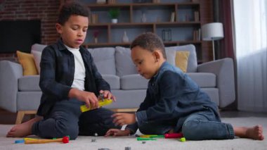 İki sevimli Afro-Amerikalı çocuk evde oyuncaklarla oynuyorlar eğleniyorlar çocuklar eğleniyorlar küçük kardeşler kardeşler oyun oynuyorlar mutlu aile hafta sonu hobileri birlikte neşe