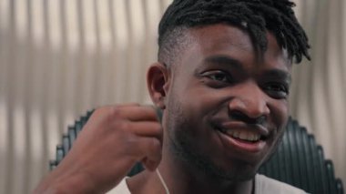Afro-Amerikalı gülümseyen siber adam, kablo kulaklık takıyor, müzik dinliyor, boş zamanın tadını çıkarıyor. Kapalı mekanlarda dinleniyor, erkek erkeğe gülümsüyor, kulaklık takıyor.
