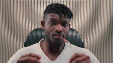 Beyaz fütürizm stüdyosuna gözlük takan şık, ciddi Afrikalı Amerikalı adam güneş gözlüğü takan modern erkek adam. Moda tarzı poz veriyor.