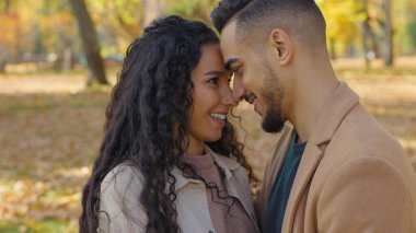 Tebessüm eden İspanyol çiftin alnına dokunan gülümseme burunlarını öpüyor Arap erkek beyaz kadın çok ırklı aşık aile fertleri güz parkında sevgili ilişkileri mutlu