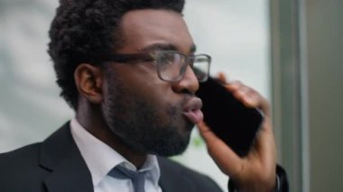 Öfkeli yetkili Afrikalı Amerikalı erkek iş adamı ofiste cep telefonu çakışmalarında bağıran erkek işadamı akıllı telefon görüşmeleri kötü iş iletişimi yanlış anlaşılmalarını bağırarak suçluyor