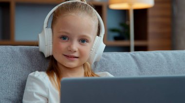 Kafkasyalı, kulaklıklı, dizüstü bilgisayarlı, kameraya bakan, bilgisayar oynayan, çocuk portresi yapan, ekrana bakan, çizgi film izleyen, internetteki kursları izleyen mutlu kız çocuğu.