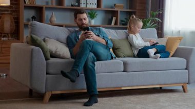 Kafkas aile aleti bağımlılığı sorunu, küçük kız çocuğuna odaklanmış, baba evde oturma odasında kaydırma uygulamaları, çocuk kızını babasından ayırmak için çeşitli cihazlar, cep telefonları, internet...