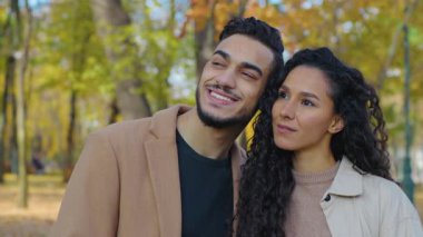 Yakın planda mutlu İspanyol çift gülen dişlek, sonbahar parkında kucaklaşan, sarılan Arap aile kucaklaşmasını seven açık havada sarılan, güler yüzlü, evli, kadın ve sonbaharda düşen adama bakan.