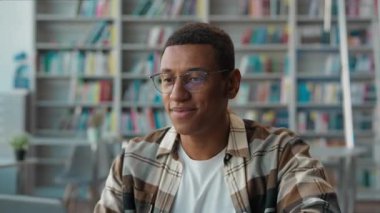 Üniversite kütüphanesinde bilgisayarını kapatan gururlu Afrikalı Amerikalı erkek öğrenci. Görev başarısı. Gülümseyen, son teslim tarihini tamamlayan erkek.