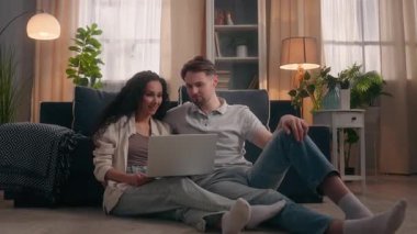 Gülümseyen beyaz erkek Latin Arap kadın online alışveriş dizüstü bilgisayarı başarısını kutluyor ev mutlu ortaklar beşer takım çalışması işbirliği yapıyor aile sevgisi anı satın alınıyor birlikte neşeyle kazanın