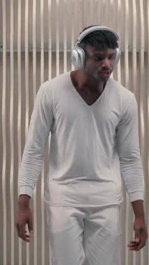 Afrikalı Amerikalı erkek dans modern kablosuz kulaklıklarla müzik dinlemeyi sever. Fütürist erkek kulaklık takıyor. Fütürizm odasında dans ediyor.