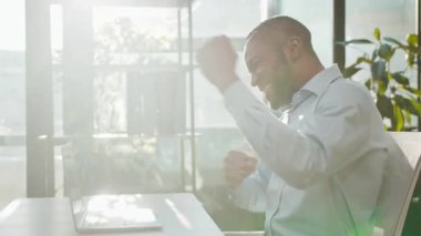 African American business man businessman winner with laptop winning dancing moving manager employer celebrate victory win online bet on computer finance growth at office yes gesture dance sunny light