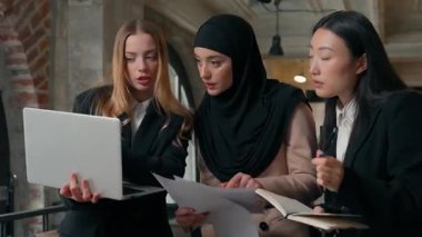 İşyerinde konsantre çalışma süreci üç çok ırklı iş kadını kız iş kadını iş hakkında konuşan Müslüman Asyalı Kafkasyalı kadınlar dizüstü bilgisayar proje toplantısını tartıştılar