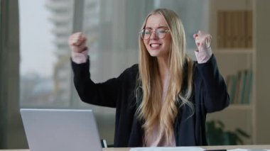 Başarılı Kafkasyalı iş kadını laptopla kazanıyor. Ofiste iyi haberler okuyor. İş kadını seviniyor.