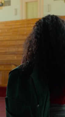 İspanyol öğrenci üniversite konferans salonuna giriyor. Şaşkın bakışlar atıyor. Latin kadın beyaz kadın hayrete düşüyor.