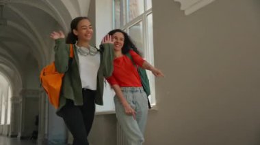 İki çok ırklı kız öğrenci üniversite koridorunda dans ediyor çok ırklı kadın arkadaş çeşitliliği Latin kökenli üniversite akademisine gidiyor iyi ruhsal durum sınavı