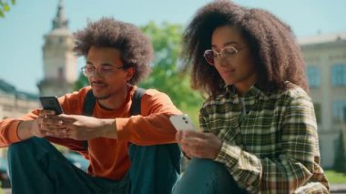 Afro-Amerikalı öğrenciler cep telefonlarını açık hava sosyal medya bağımlılığı üniversitesi iki akıllı telefon bağımlısı erkek öğrenci erkek öğrenci çift kız arkadaş kadın şehir kadını