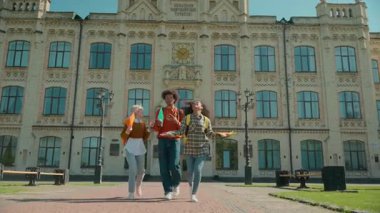 Mutlu çok ırklı üç öğrenci kutluyor hava yürüyüşü yapan üniversite Kafkas kız kadın Afrikalı erkek erkek sınıf arkadaşları üniversiteden mezun olup sınavlara giriyor.