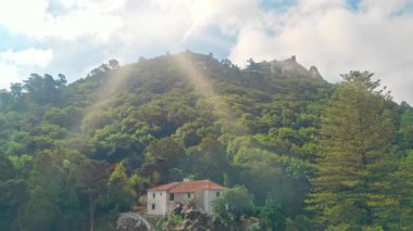 Sintra Portekiz 'deki yeşil orman tepelerinin hava manzarası. Güneş ışınları parlıyor. Gökyüzü bulutları, ağaçlar, dağ manzarası.