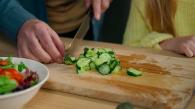 Mutfakta tanınmayan Kafkas ailesini kapatın. Birlikte yemek pişirin. Baba, salatalık doğrayın. Kızla birlikte taze sebze vitamin salatası pişirin.