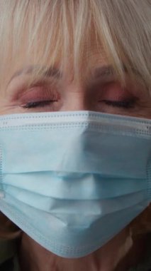 Yakın plan beyaz kadın. Kapalı alanda, bej renkli stüdyoda tıbbi yüz maskesi portresi çıkarıyor. Salgın salgını durdurma salgını sona eriyor.