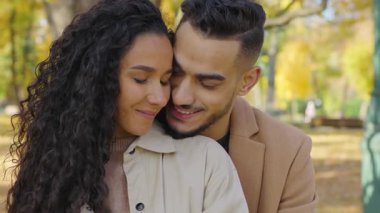 Sonbahar parkında sarılıp kucaklaşan İspanyol çift. Sevgili Arap erkeği kucaklaşması. Arka planda romantik balayından sevgili bir kadına sarılmak.